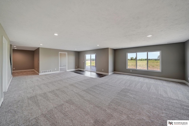 unfurnished living room featuring a healthy amount of sunlight, baseboards, visible vents, and light colored carpet