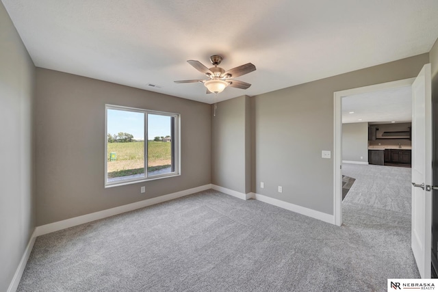 unfurnished room with baseboards, a ceiling fan, visible vents, and light colored carpet