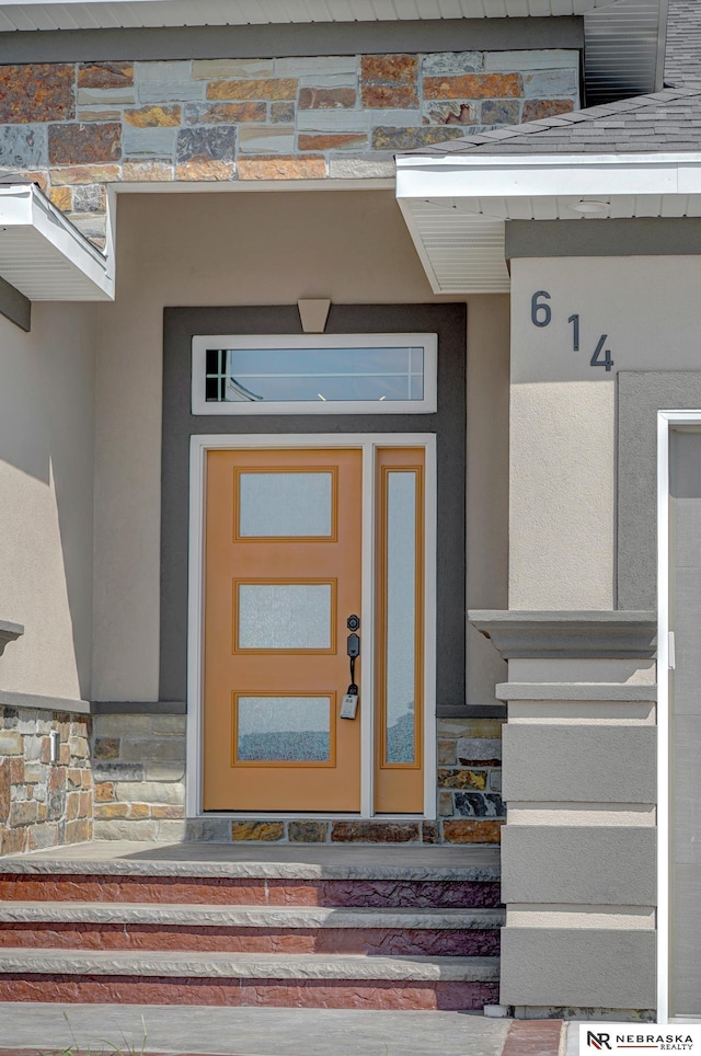 doorway to property featuring stone siding and stucco siding