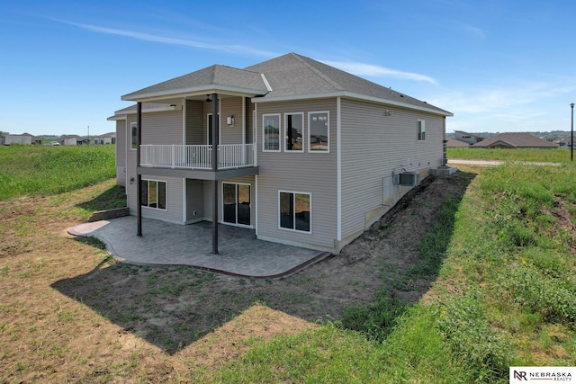 back of property featuring cooling unit, a patio area, a yard, and roof with shingles