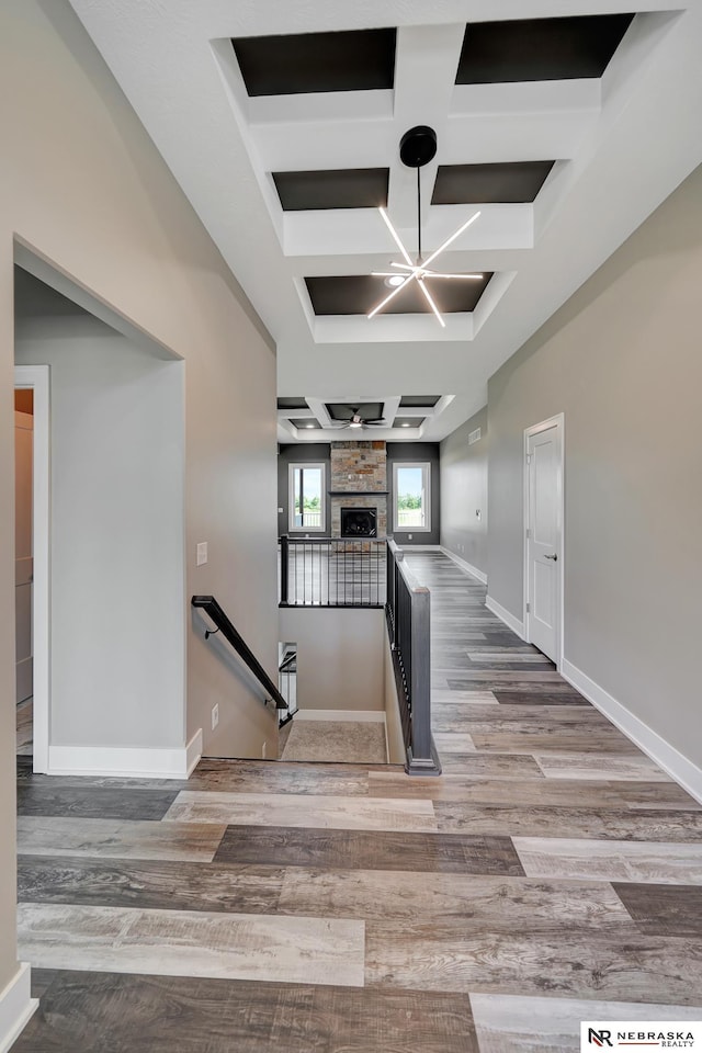 staircase with a fireplace, baseboards, coffered ceiling, and wood finished floors