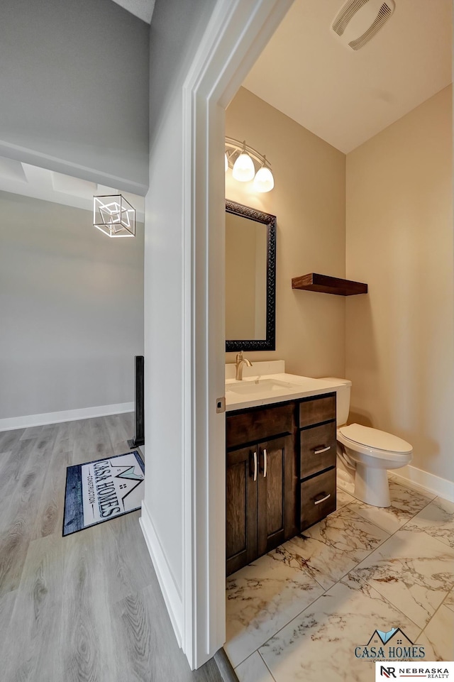 half bathroom with baseboards, visible vents, toilet, marble finish floor, and vanity