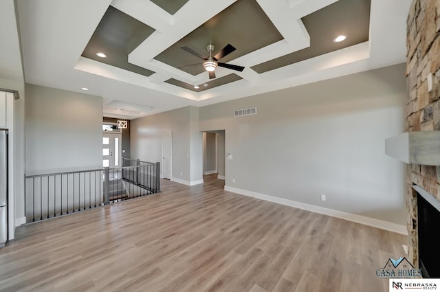 unfurnished living room featuring light wood finished floors, baseboards, visible vents, coffered ceiling, and a fireplace