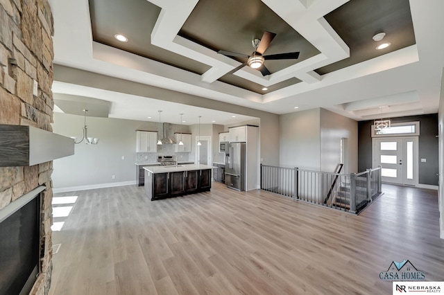 unfurnished living room featuring light wood-style floors, a fireplace, baseboards, and a raised ceiling