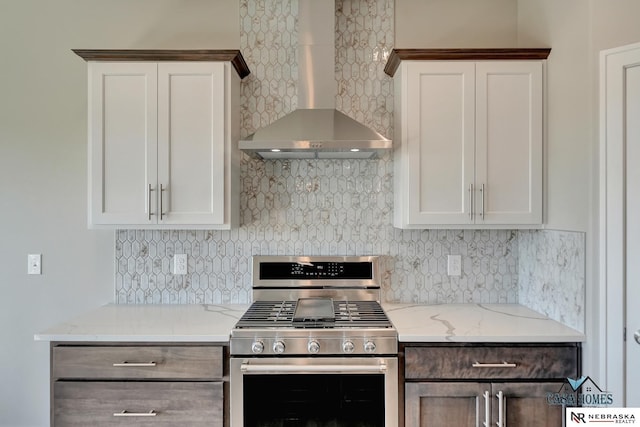 kitchen with tasteful backsplash, gas range, wall chimney exhaust hood, and white cabinets