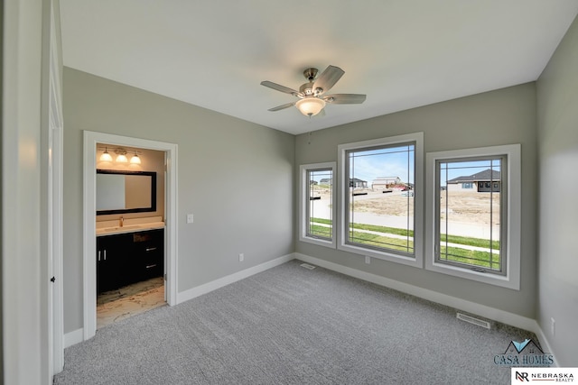 unfurnished bedroom featuring baseboards, visible vents, carpet flooring, and ensuite bathroom