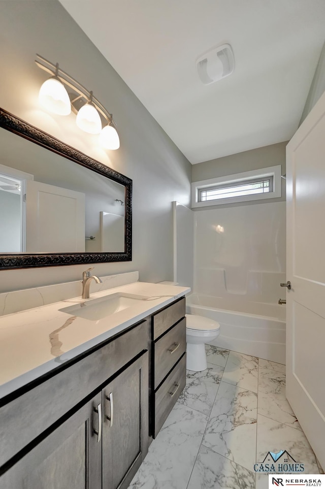 bathroom featuring marble finish floor, vanity, toilet, and bathtub / shower combination