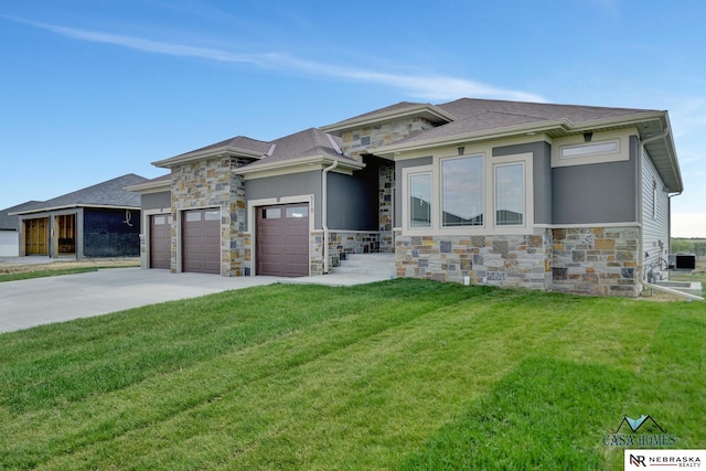 prairie-style home with stone siding, a front lawn, an attached garage, and driveway