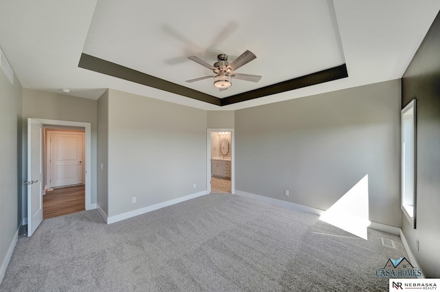 unfurnished bedroom with light carpet, visible vents, baseboards, and a raised ceiling