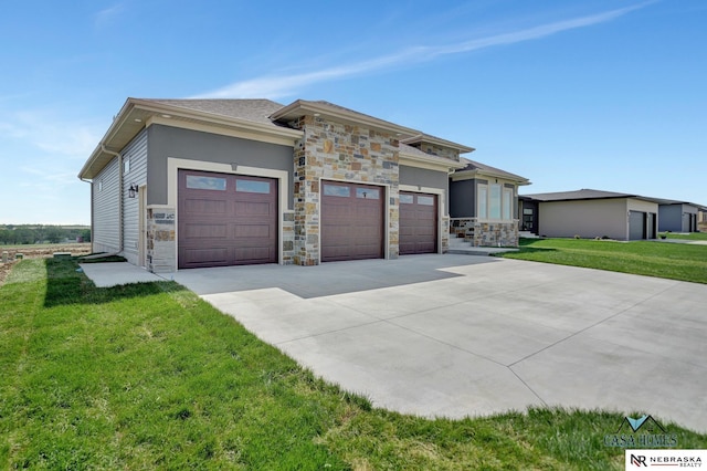 prairie-style house featuring a garage, a front yard, concrete driveway, and stone siding