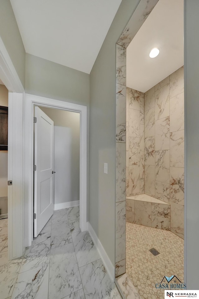 bathroom featuring marble finish floor, baseboards, and tiled shower