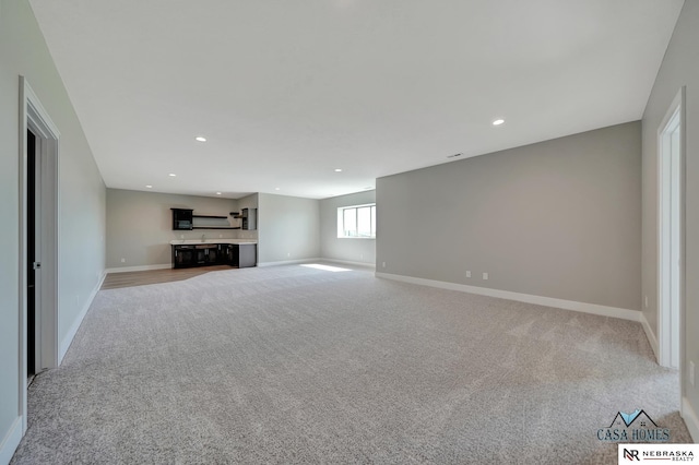 unfurnished living room with recessed lighting, light carpet, and baseboards