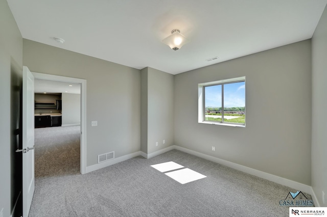 empty room with baseboards, visible vents, and light colored carpet