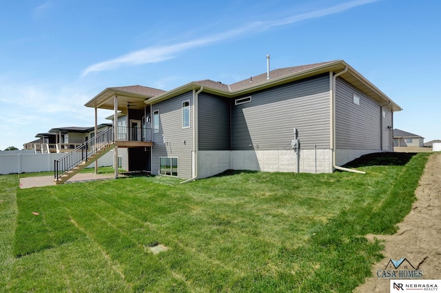 rear view of house featuring ceiling fan, stairway, fence, and a lawn