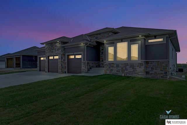 prairie-style house with an attached garage, stone siding, a lawn, and concrete driveway