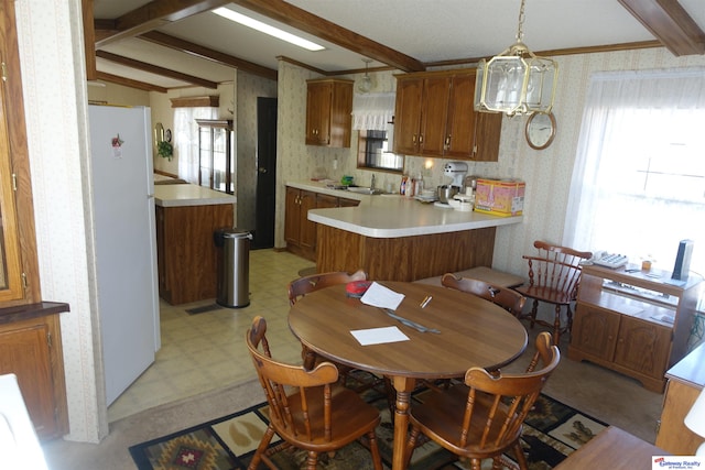 kitchen featuring light floors, light countertops, hanging light fixtures, freestanding refrigerator, and wallpapered walls