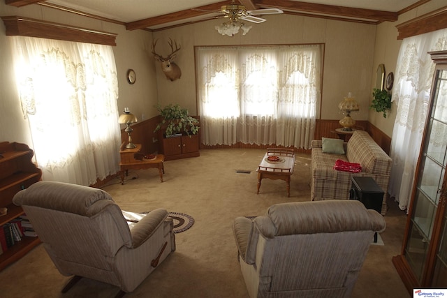 living area featuring a ceiling fan, a wealth of natural light, light colored carpet, and lofted ceiling with beams