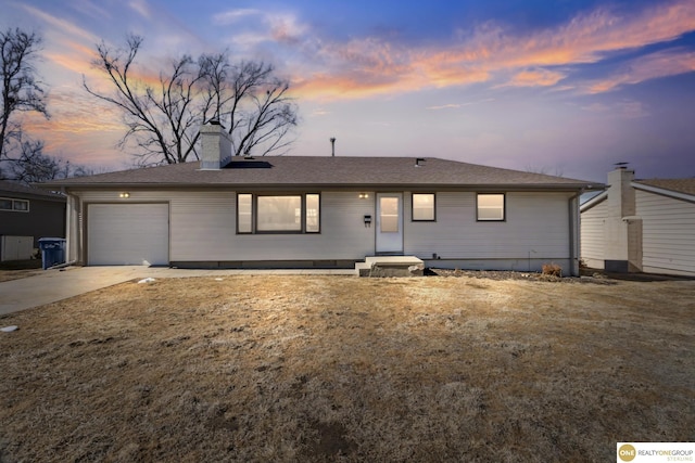 ranch-style home featuring a garage, driveway, a chimney, and a shingled roof