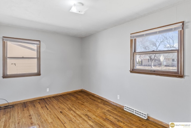 spare room with baseboards, visible vents, and wood finished floors