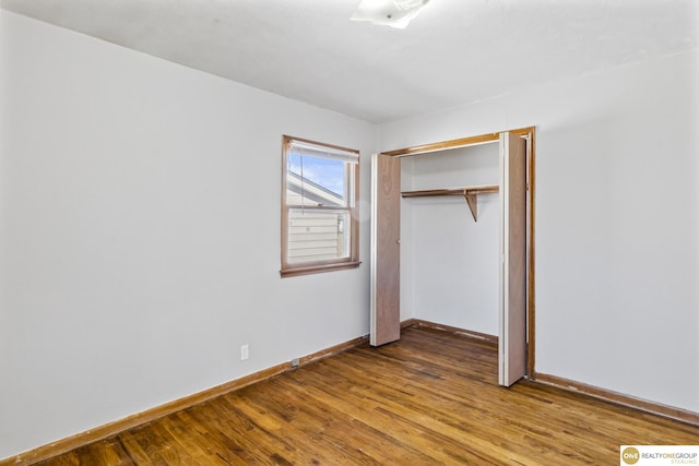 unfurnished bedroom featuring a closet, baseboards, and wood finished floors