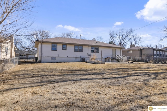 rear view of property with crawl space, fence, and a yard