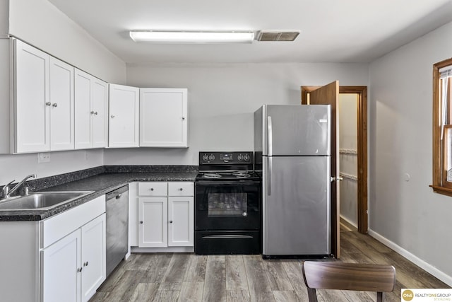 kitchen with dark countertops, appliances with stainless steel finishes, and white cabinets