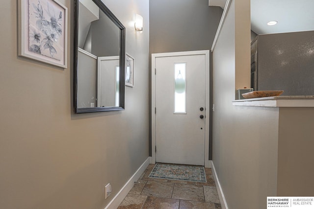 doorway with baseboards and stone tile flooring