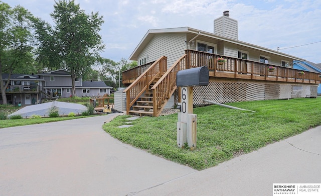 exterior space with a chimney, a deck, a front lawn, and stairs