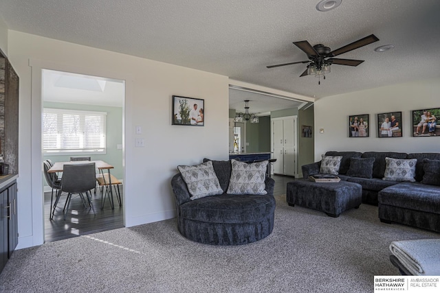 living room featuring dark colored carpet, a textured ceiling, and ceiling fan with notable chandelier