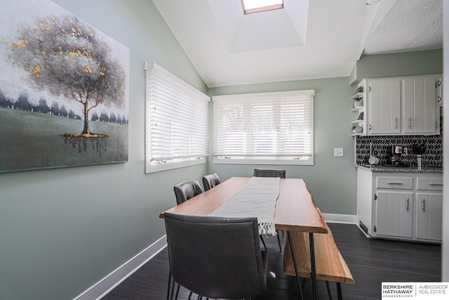 dining room featuring lofted ceiling with skylight, baseboards, dark wood finished floors, and a textured ceiling