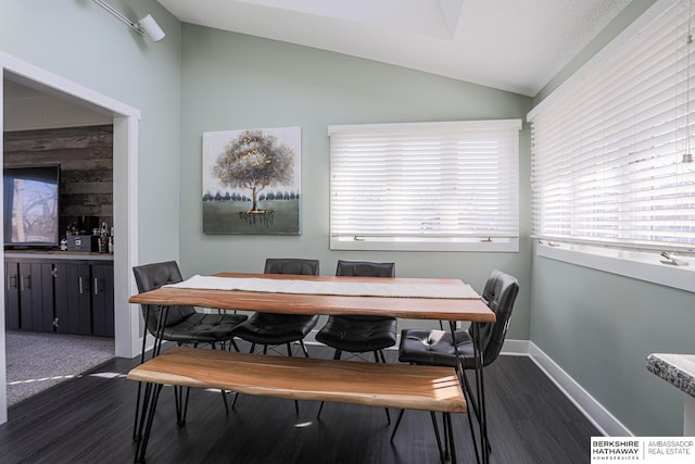 dining area featuring lofted ceiling, dark wood-style flooring, and baseboards