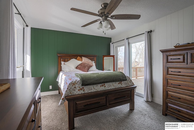 carpeted bedroom with access to outside, baseboards, ceiling fan, and a textured ceiling