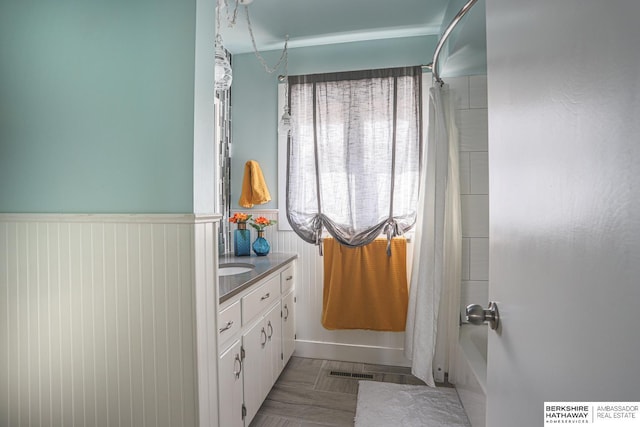 full bath featuring wainscoting, shower / bath combo, visible vents, and vanity