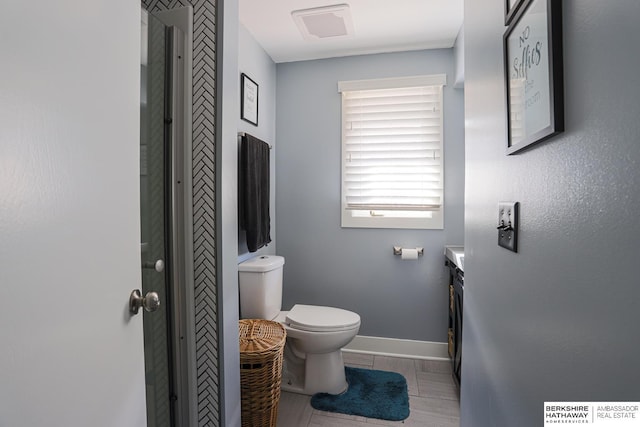 bathroom featuring toilet, visible vents, vanity, baseboards, and walk in shower