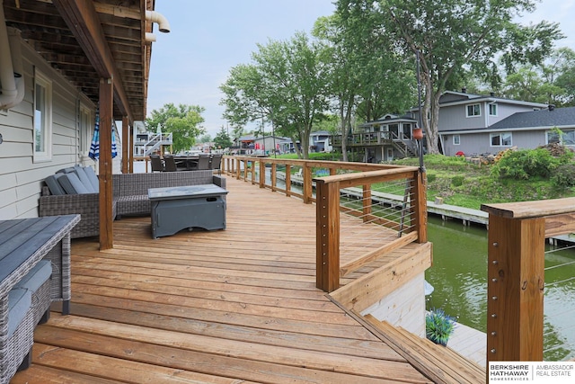 wooden deck featuring a water view and an outdoor living space