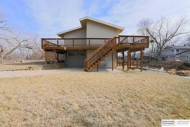 rear view of house featuring stairway, driveway, a deck, and a garage