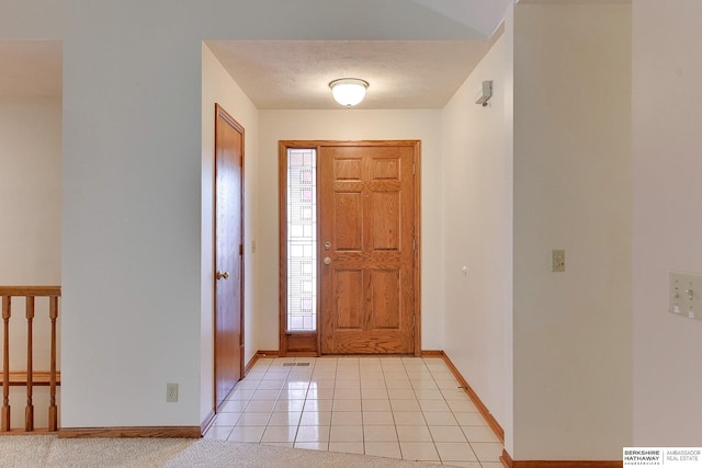 foyer featuring light tile patterned floors, baseboards, and a textured ceiling