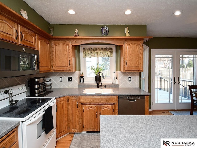 kitchen with brown cabinetry, french doors, a sink, and black appliances