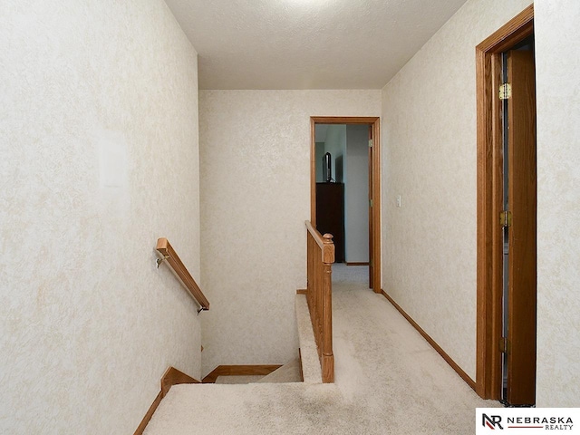 staircase with carpet floors and a textured wall