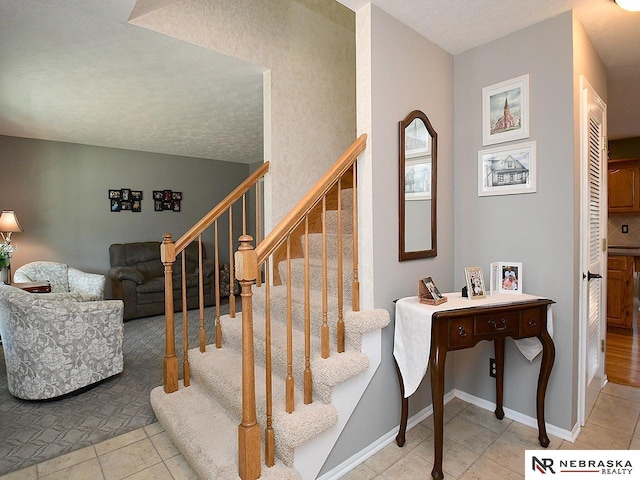 stairway featuring a textured ceiling, baseboards, and tile patterned floors