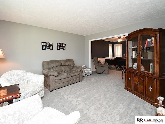 living room with a textured ceiling, light carpet, and a ceiling fan