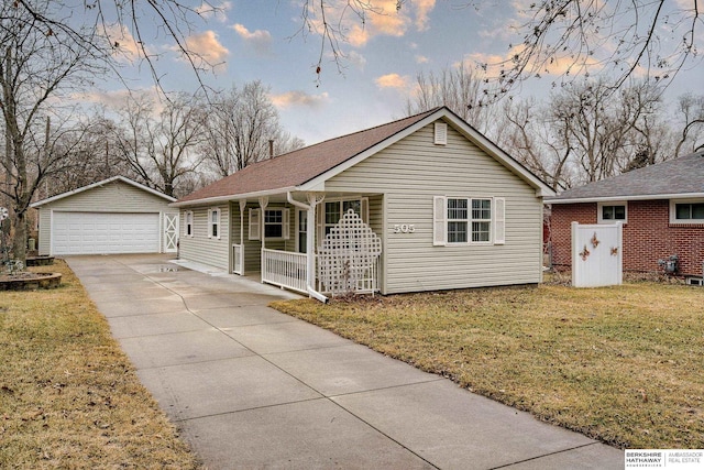 view of front of house with a yard, a detached garage, a porch, and an outbuilding