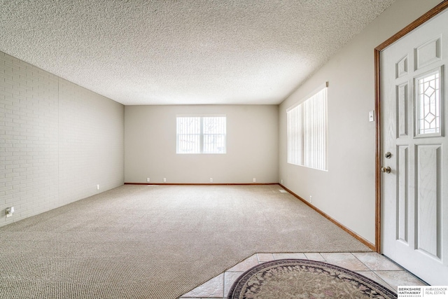 entryway featuring baseboards, brick wall, tile patterned floors, a textured ceiling, and carpet flooring