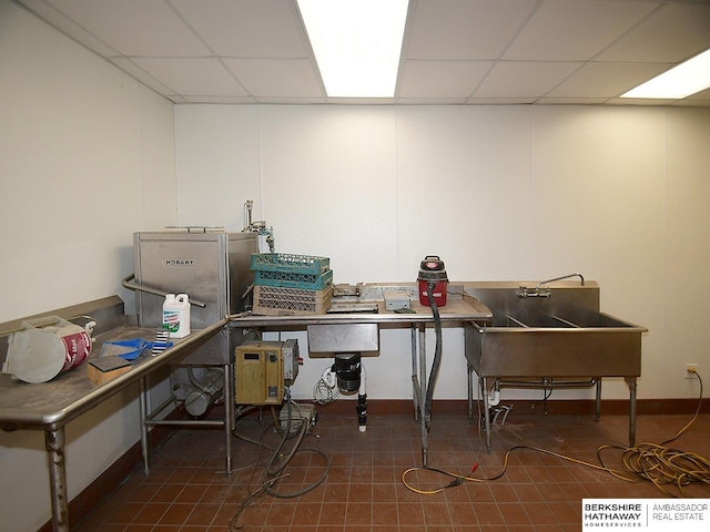 office with baseboards, a drop ceiling, a sink, and tile patterned floors