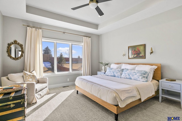 bedroom featuring baseboards, ceiling fan, a raised ceiling, and light colored carpet