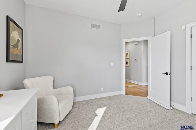 living area with light carpet, a ceiling fan, visible vents, and baseboards