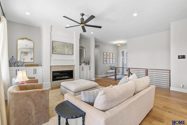 living area featuring light wood-type flooring, baseboards, recessed lighting, and a tile fireplace