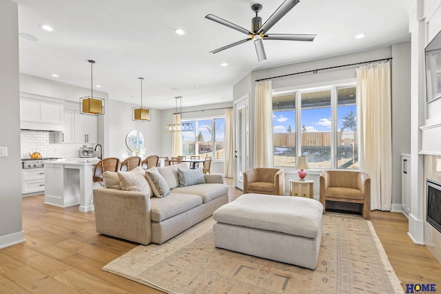 living area featuring a ceiling fan, a fireplace, light wood-style flooring, and recessed lighting