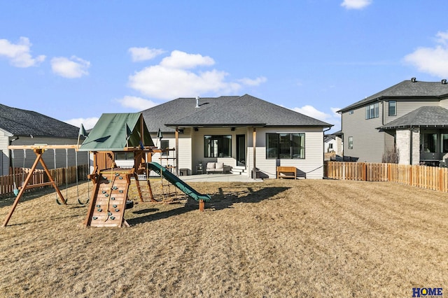 back of house with a patio area, a shingled roof, fence, and a playground