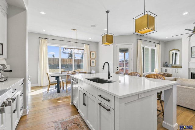 kitchen featuring a sink, white cabinets, open floor plan, light countertops, and an island with sink